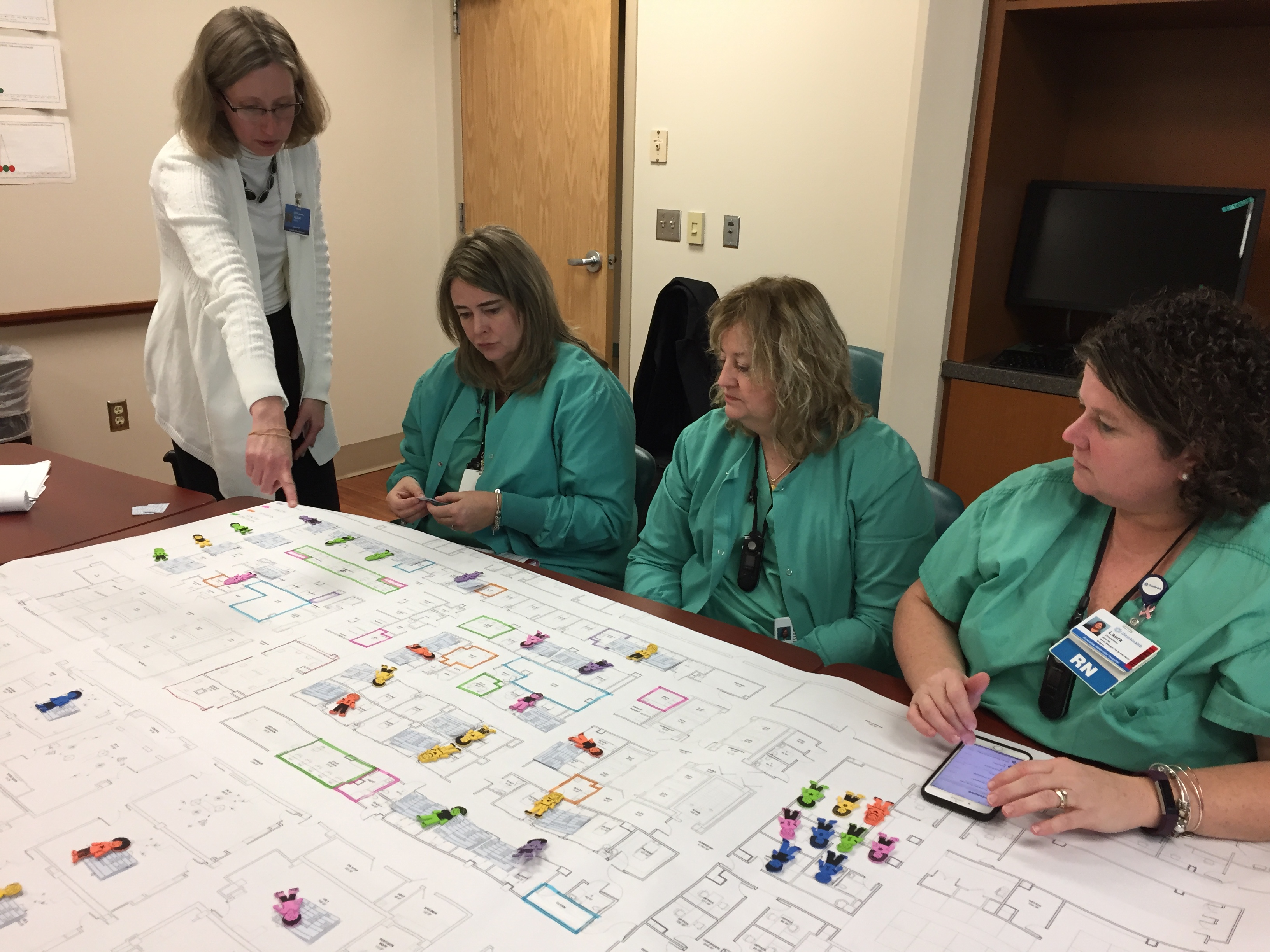 Group of nurses reviewing a large diagram on a table.