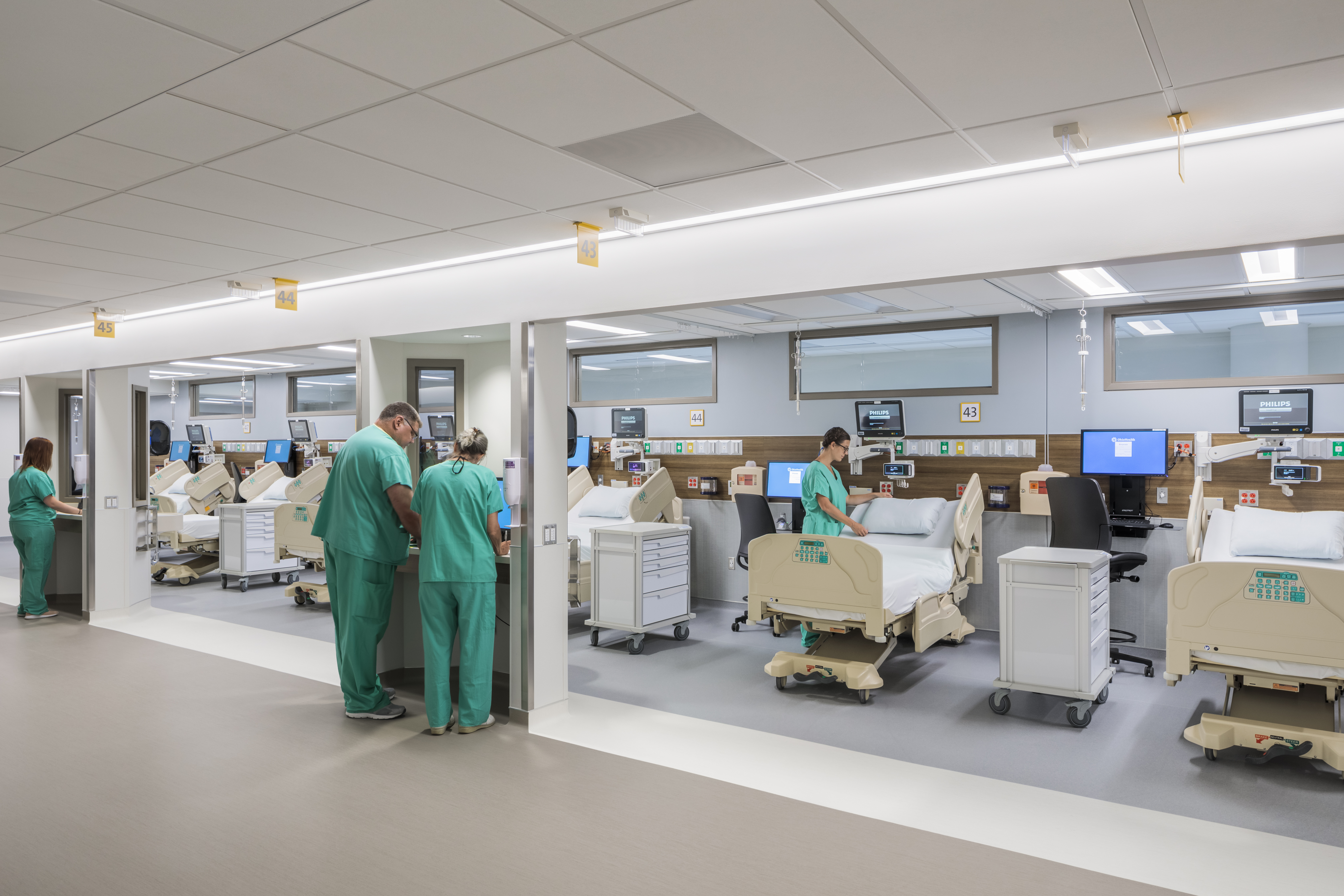 Medical bay with doctors and nursing working at computers or preparing hospital beds.