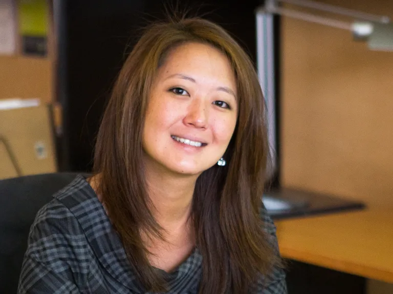 Alana Haslow smiling while wearing a dark grey tartan plaid blouse