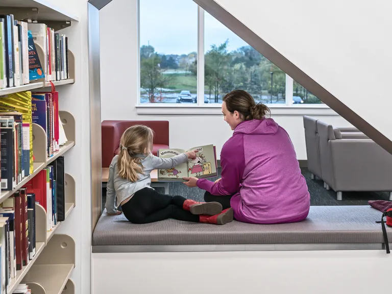 Person reading to a child in a library.
