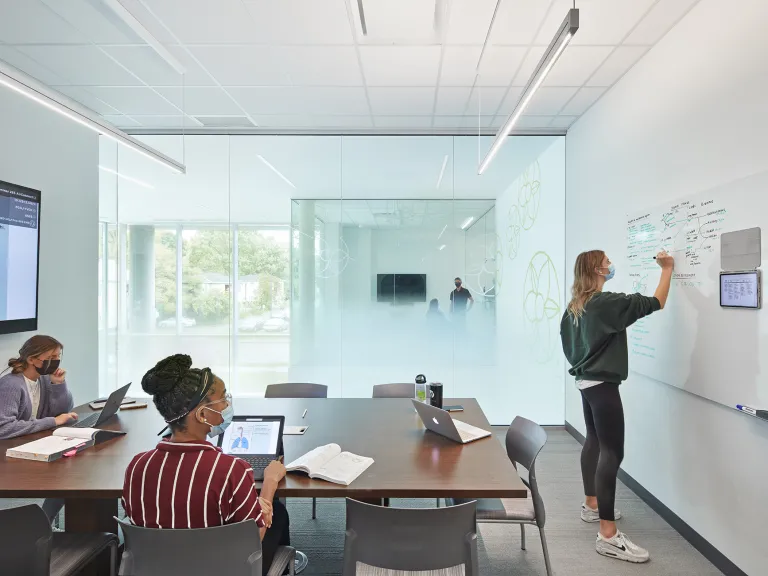 Students studying and writing on a whiteboard at Ohio University's Heritage College.