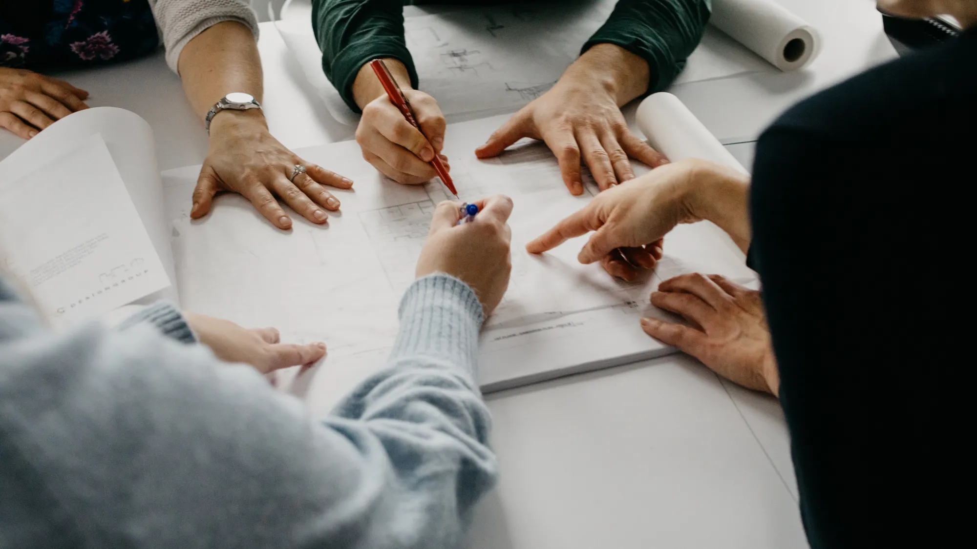 Set of hands with pens pointing and reviewing a document