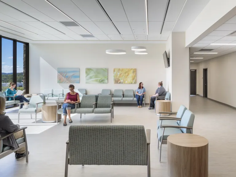 Interior waiting room during the day with various people sitting