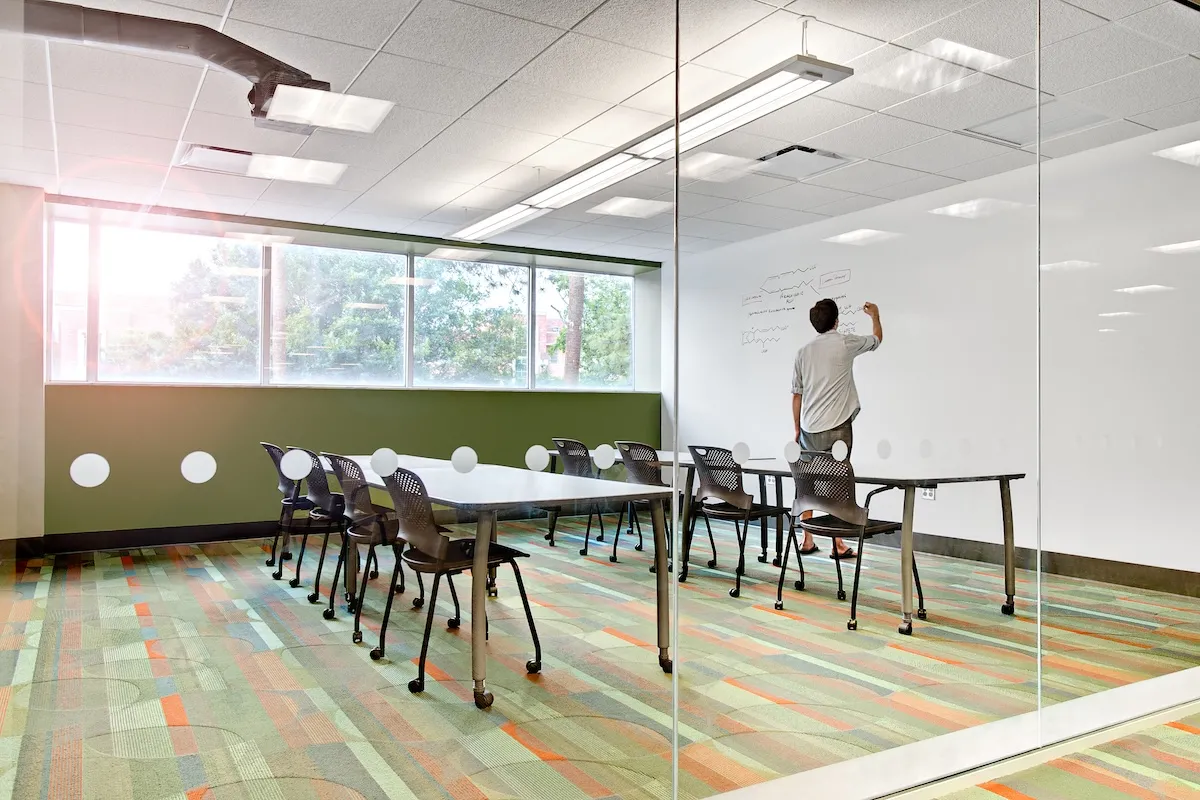 person writing on whiteboard in room