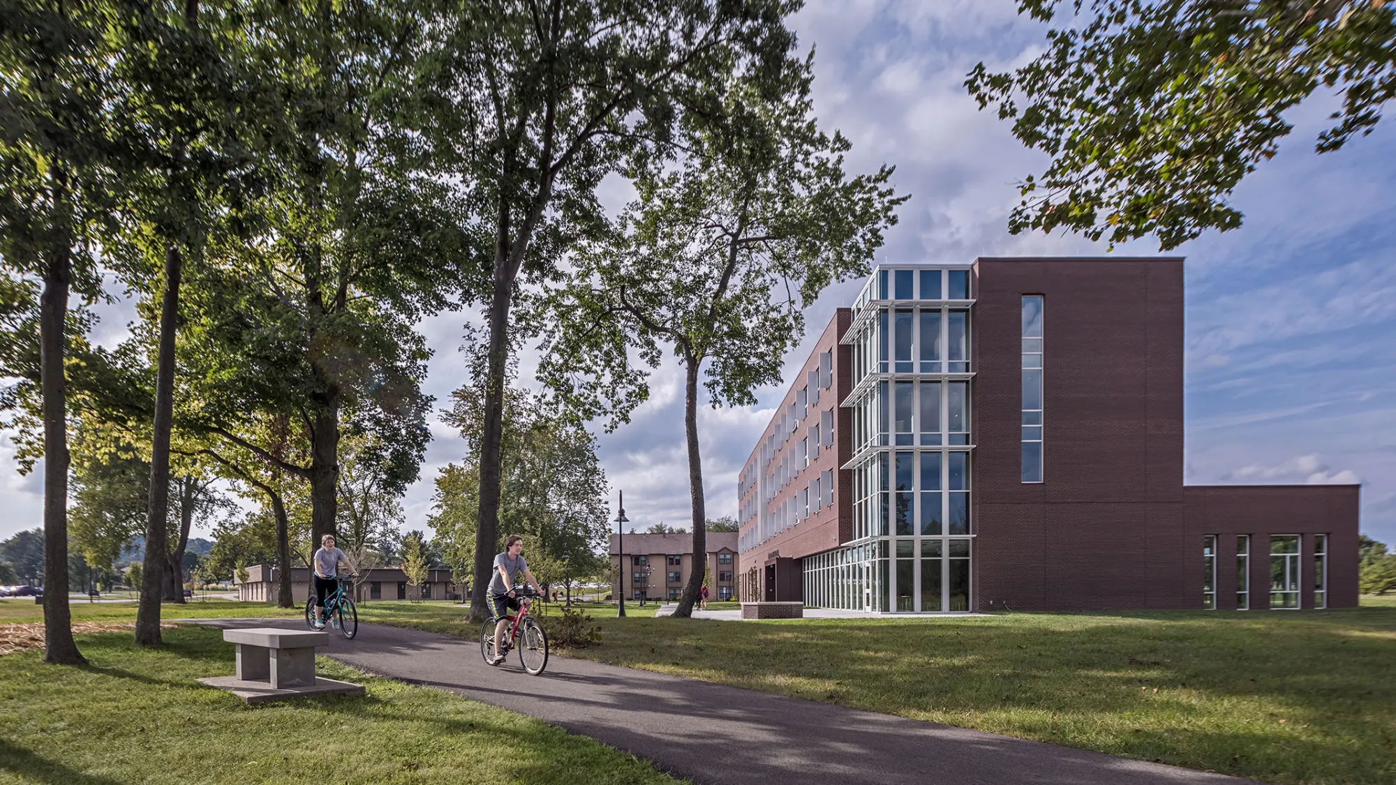 students ride bikes past residence hall on university campus