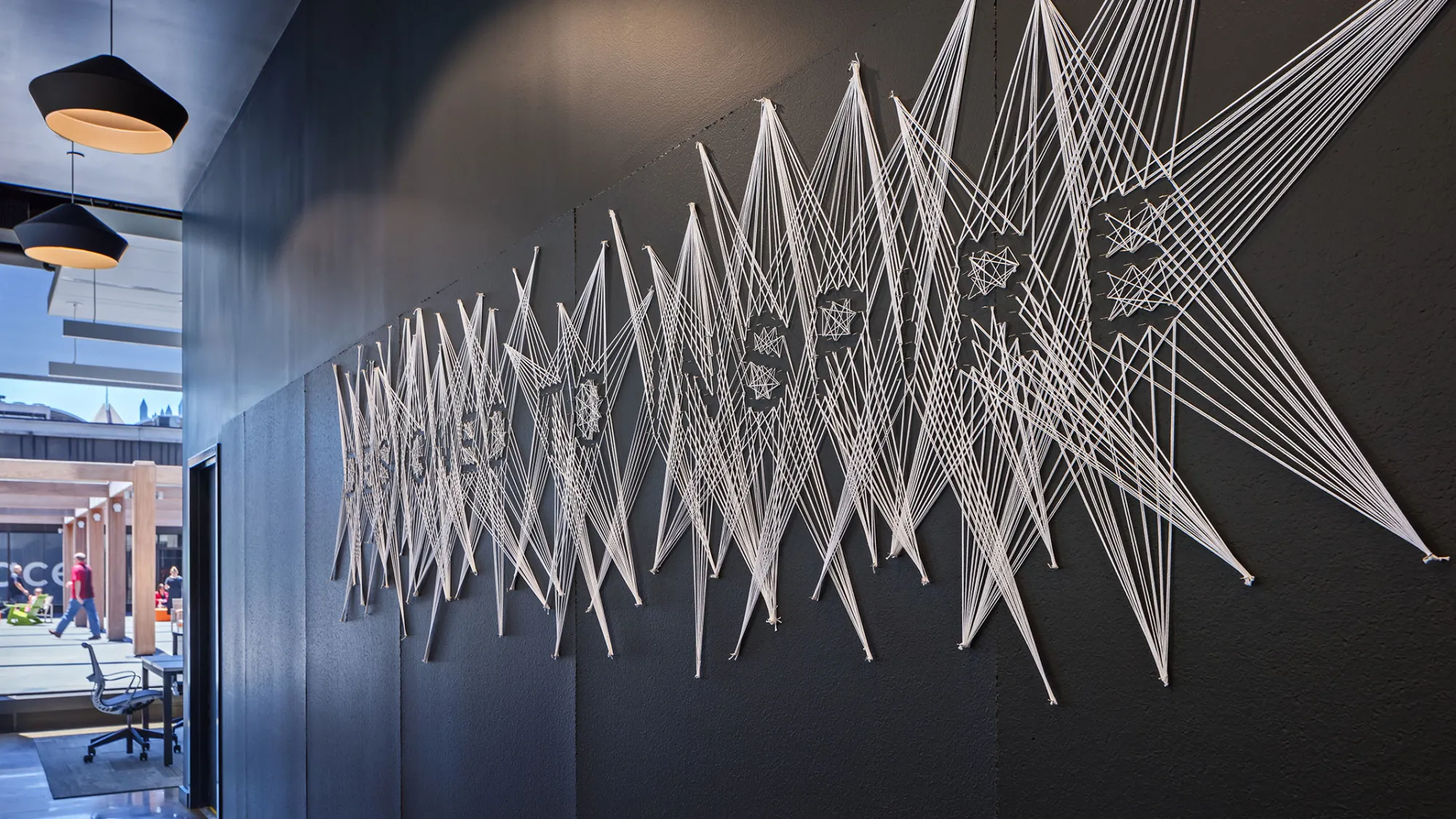 string wall art that spells "designed to inspire"