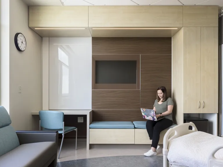 Person working on a computer in a brightly lit patient room in a medical facility.