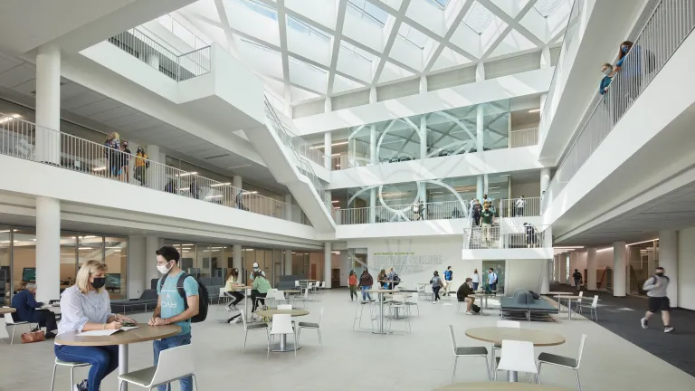 Atrium of Heritage Hall during the day, featuring tables on the ground floor with students interacting