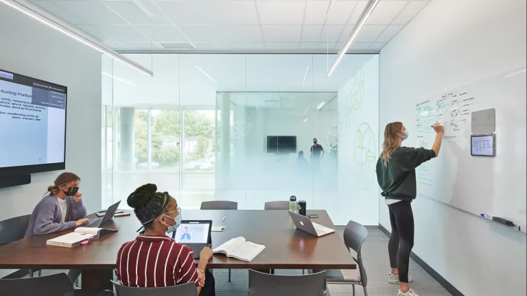 Students studying and writing on a whiteboard at Ohio University's Heritage College.