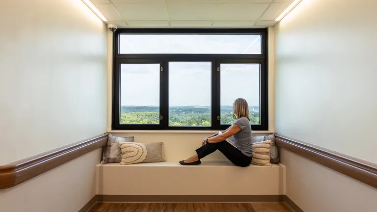 Person sitting in a window seat looking outside in a hallway of PHMV.