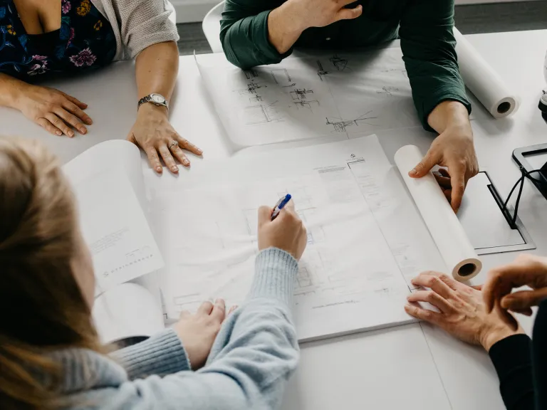 Aerial view of a group of people working on architectural plans together.
