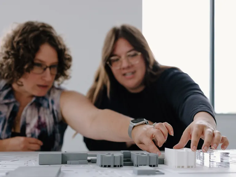 Two people talking and working with an architectural model.